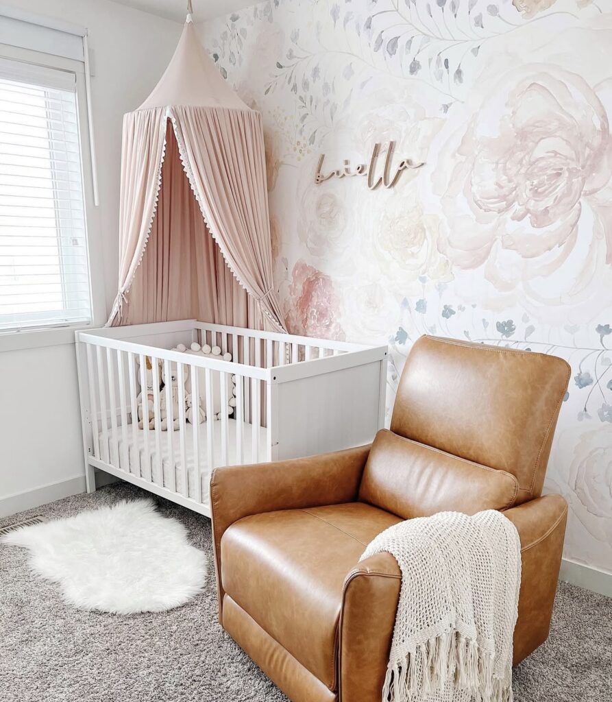 Photo of a nursery with floral wallpaper, white crib, and leather rocking chair