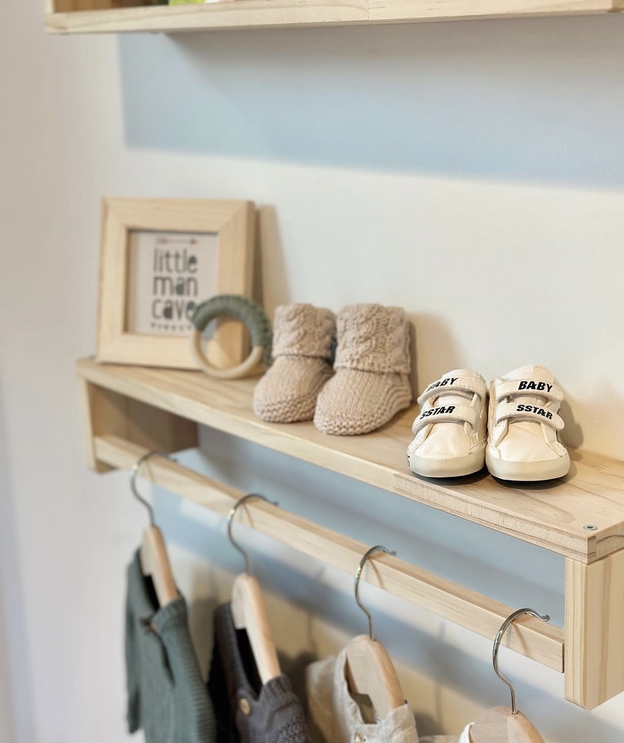 Photo of a shelf with baby shoes and baby clothes hanging from the shelf