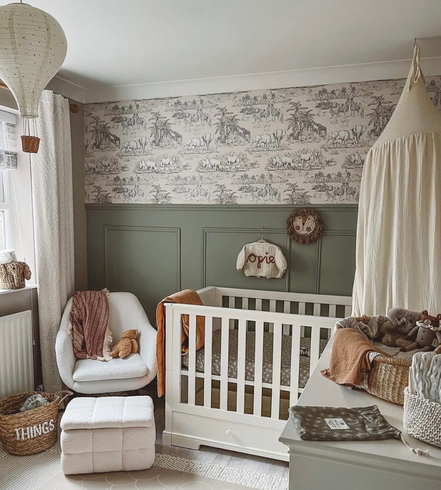 Photo of a safari themed nursery with a white crib, accent chair, and changing station. 