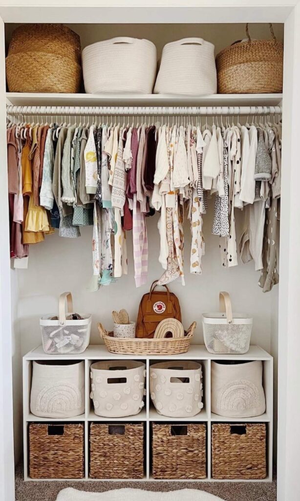 Organized nursery closet with bins, clothes, and cube dresser at the bottom of the closet