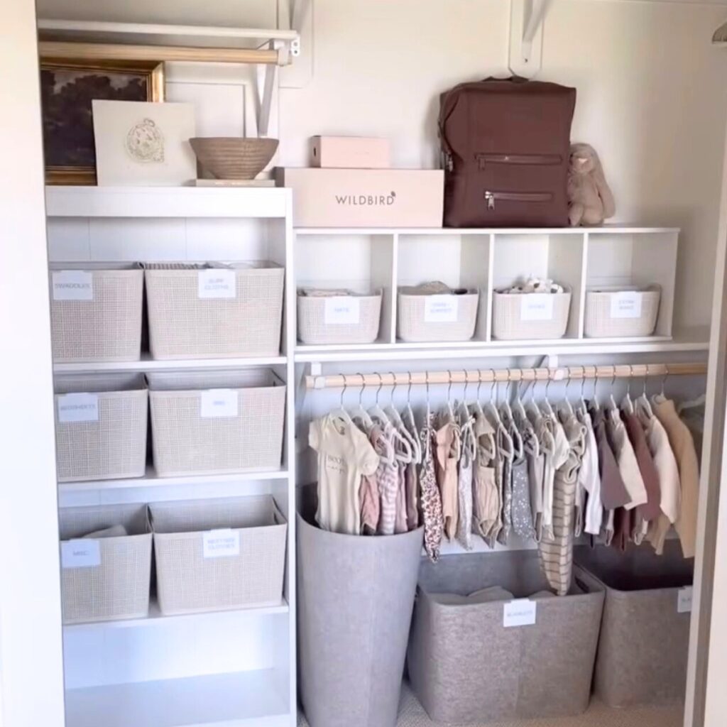 Organized nursery closet with bins, shelves, clothes, and a laundry basket