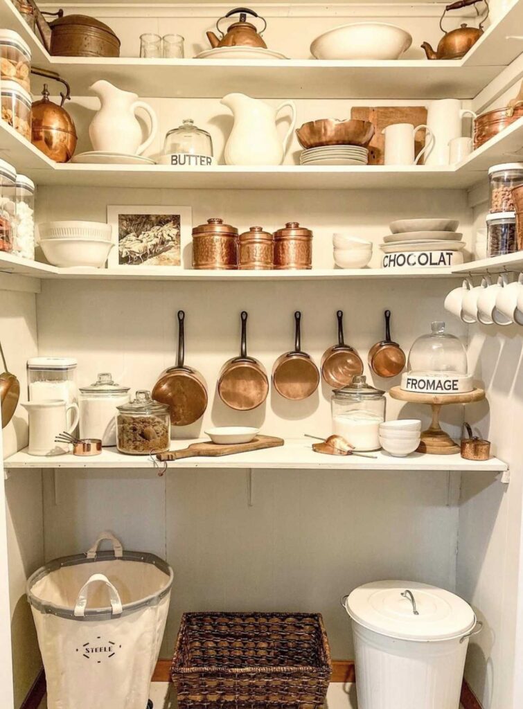 Farmhouse style pantry with white dinnerware, brass metal kitchen items, dinnerware, open shelves, and drinkware.