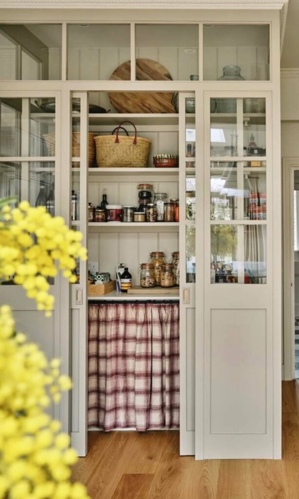 Country pantries with glass sliding door, jars, baskets, and pantry staples.