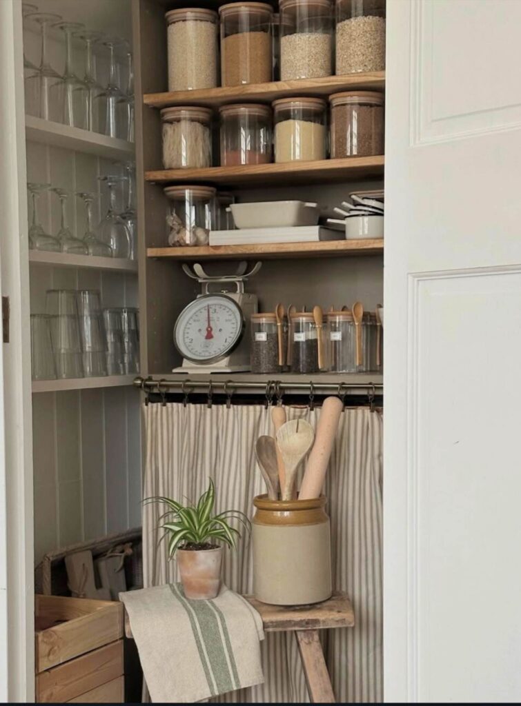 Country Pantry with jars, antique scale, drinking, glasses, cooking utensils and a stool.