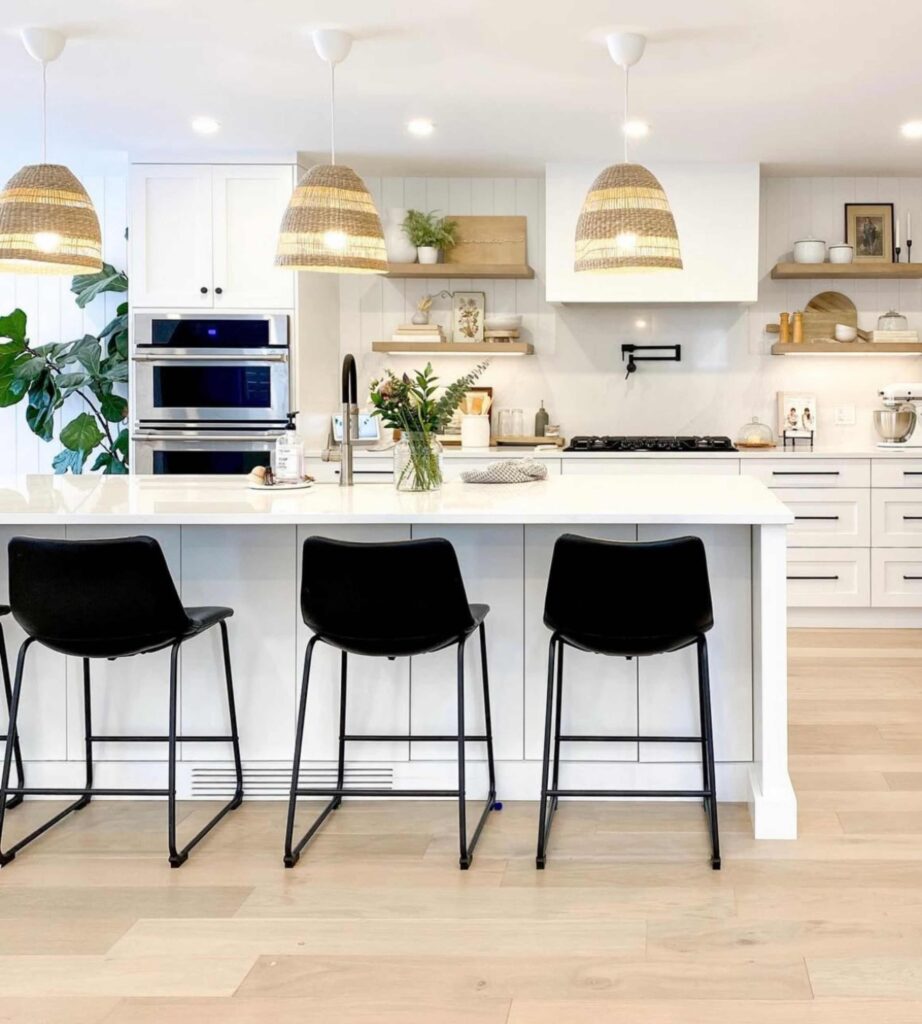 White Kitchen with center island and cabinets, stools, and shelving. 