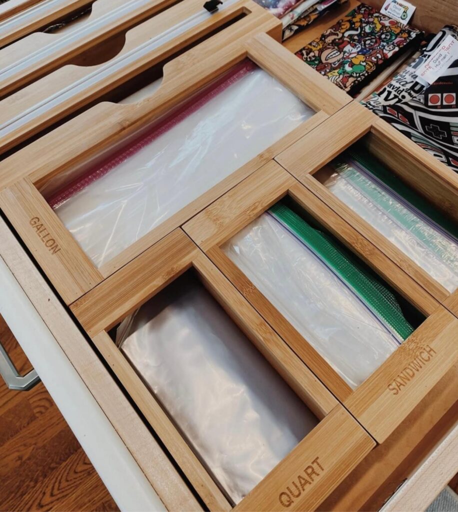 Kitchen drawer with sandwich bags, freezer bags, and snack bags stored in wooden bag dispensers. 