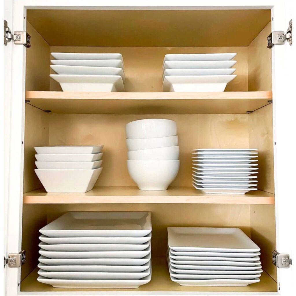 Where to put things in kitchen cabinets and drawers: picture of white plates organized neatly in a kitchen cabinet. 