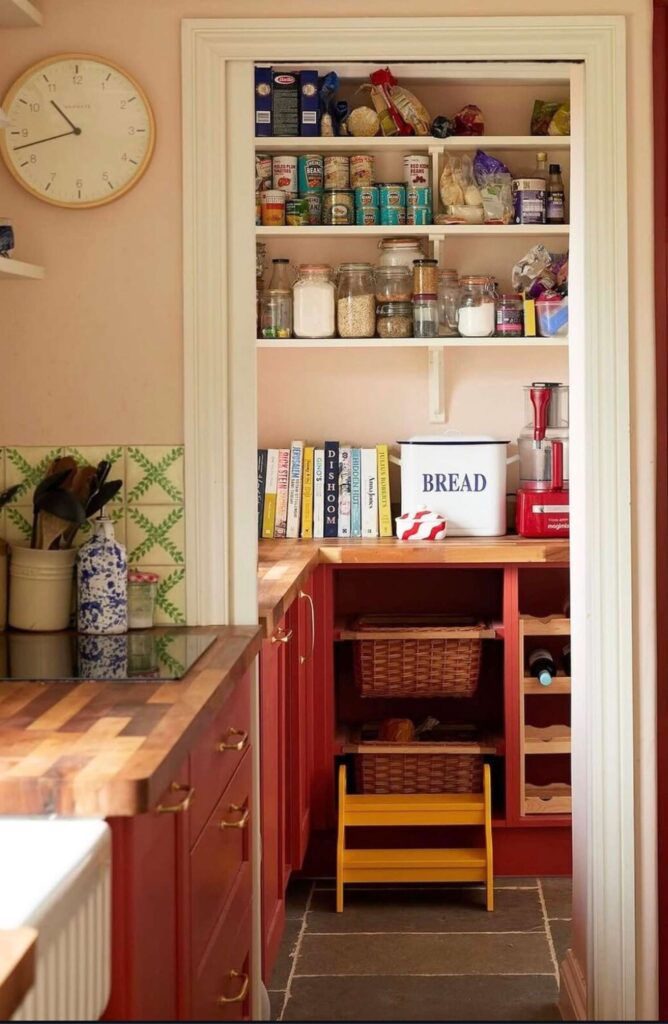 A vintage style country pantry with a large bread bin, books, jars, canned goods, and other pantry essentials.