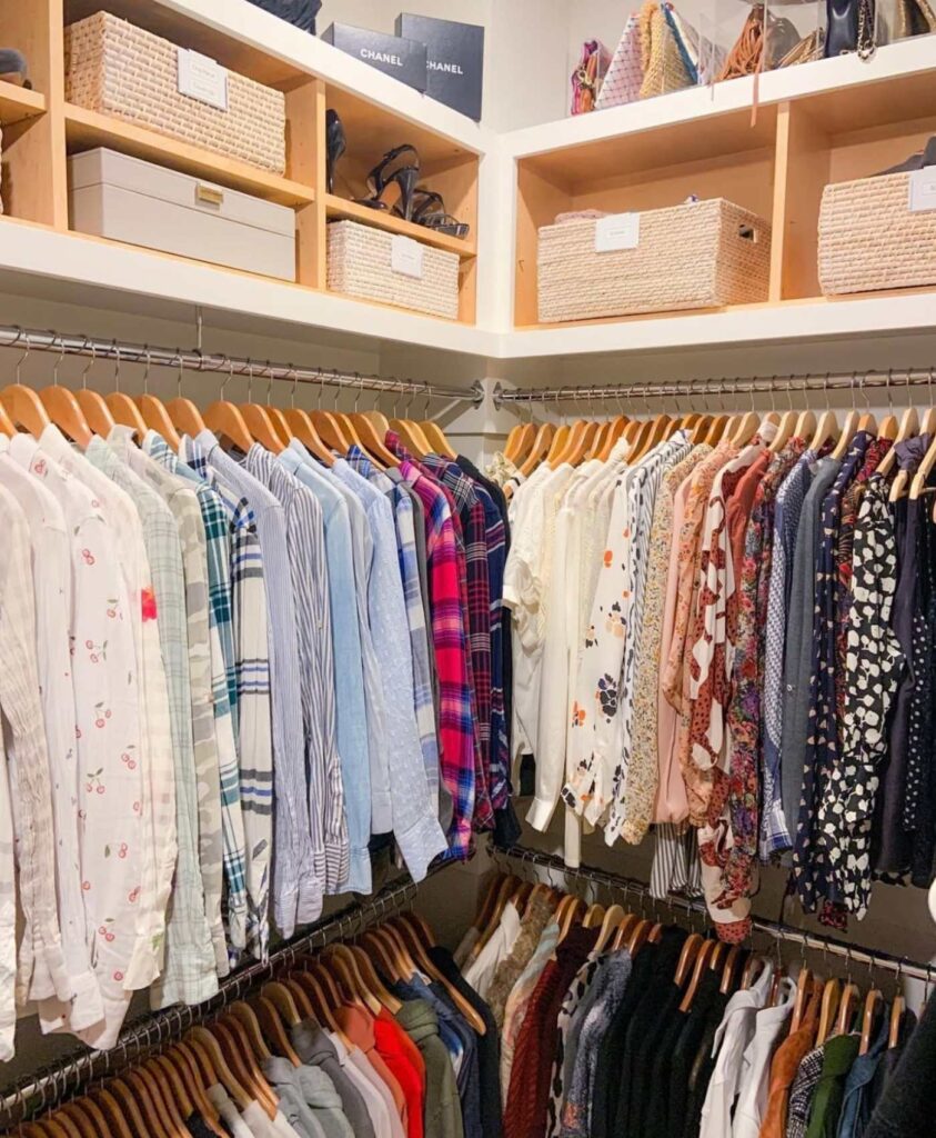 Neat and organized bedroom closet with storage bins, clothes, and purses.