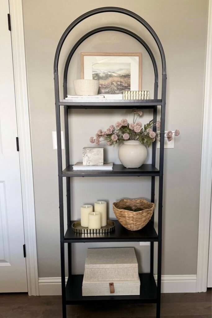 Arched shelving with decor items and bins on it.
