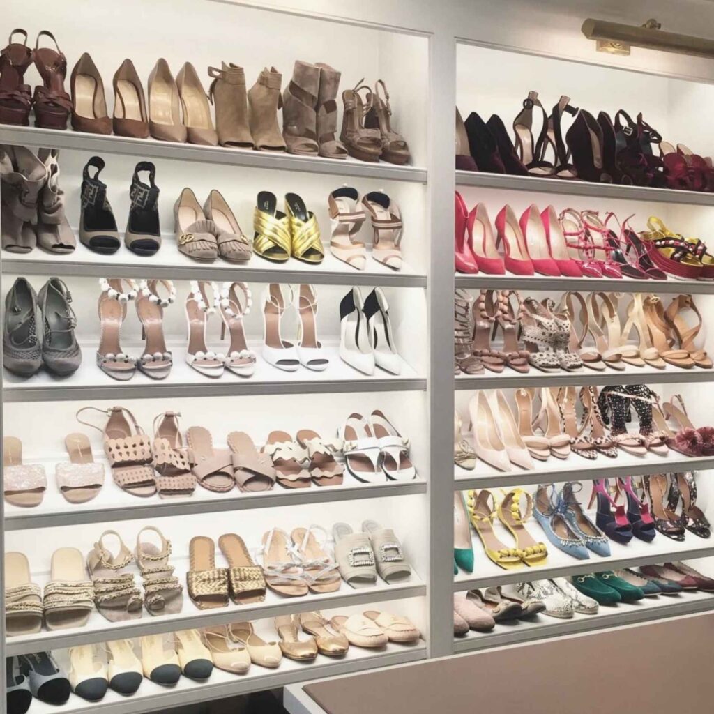 Shoes stored on shelves in a closet with lighting installed. 