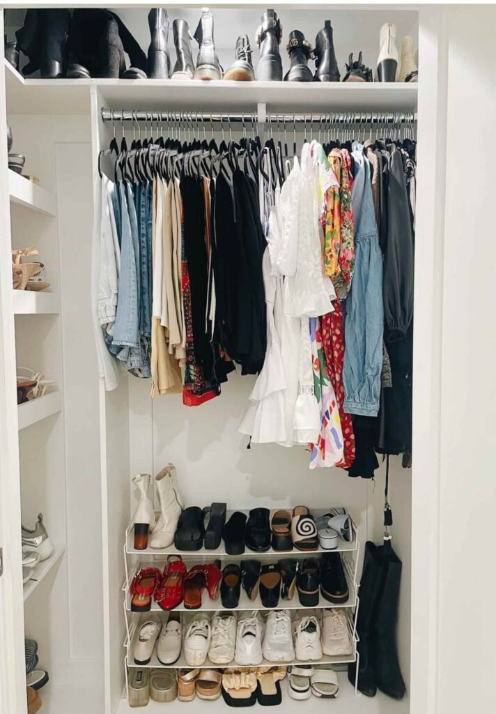 Shoe storage in a closet on a white wire shoe rack and on the top shelf of the closet