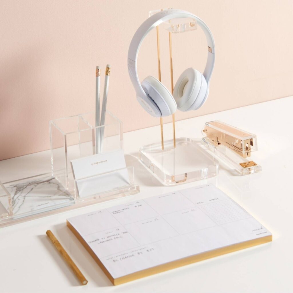 Desk with a headphone stand, planner, desk accessories organizer, and stapler. 