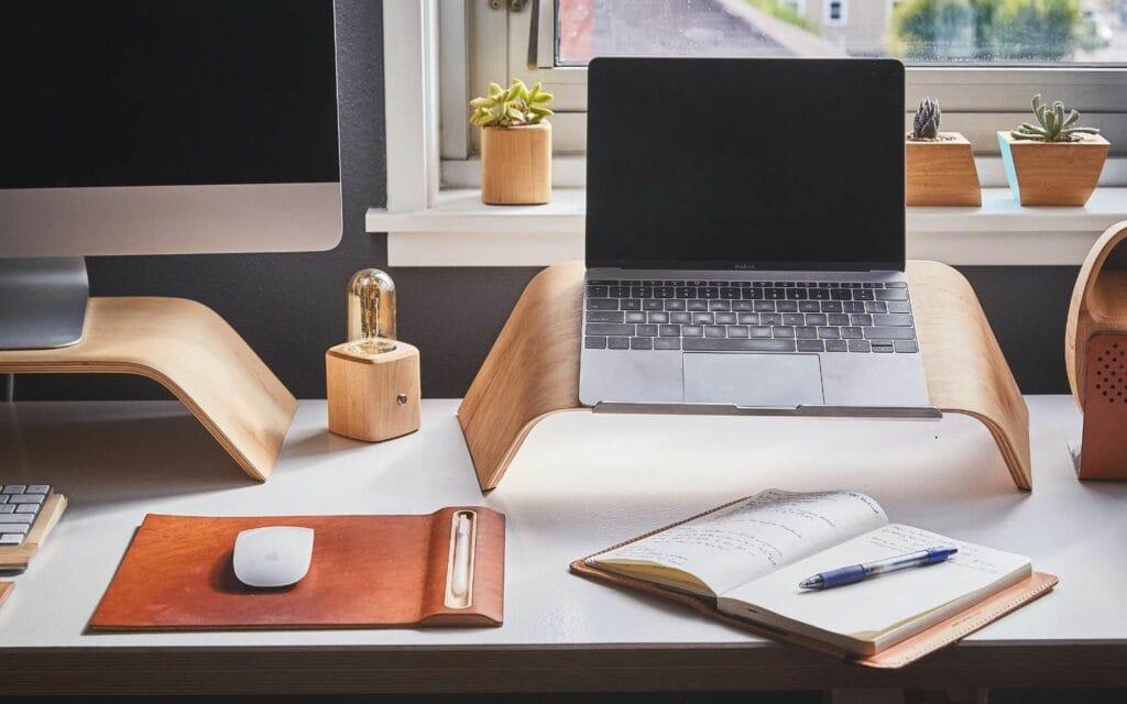 Picture of a desk with computers on wood risers on top of the desk 