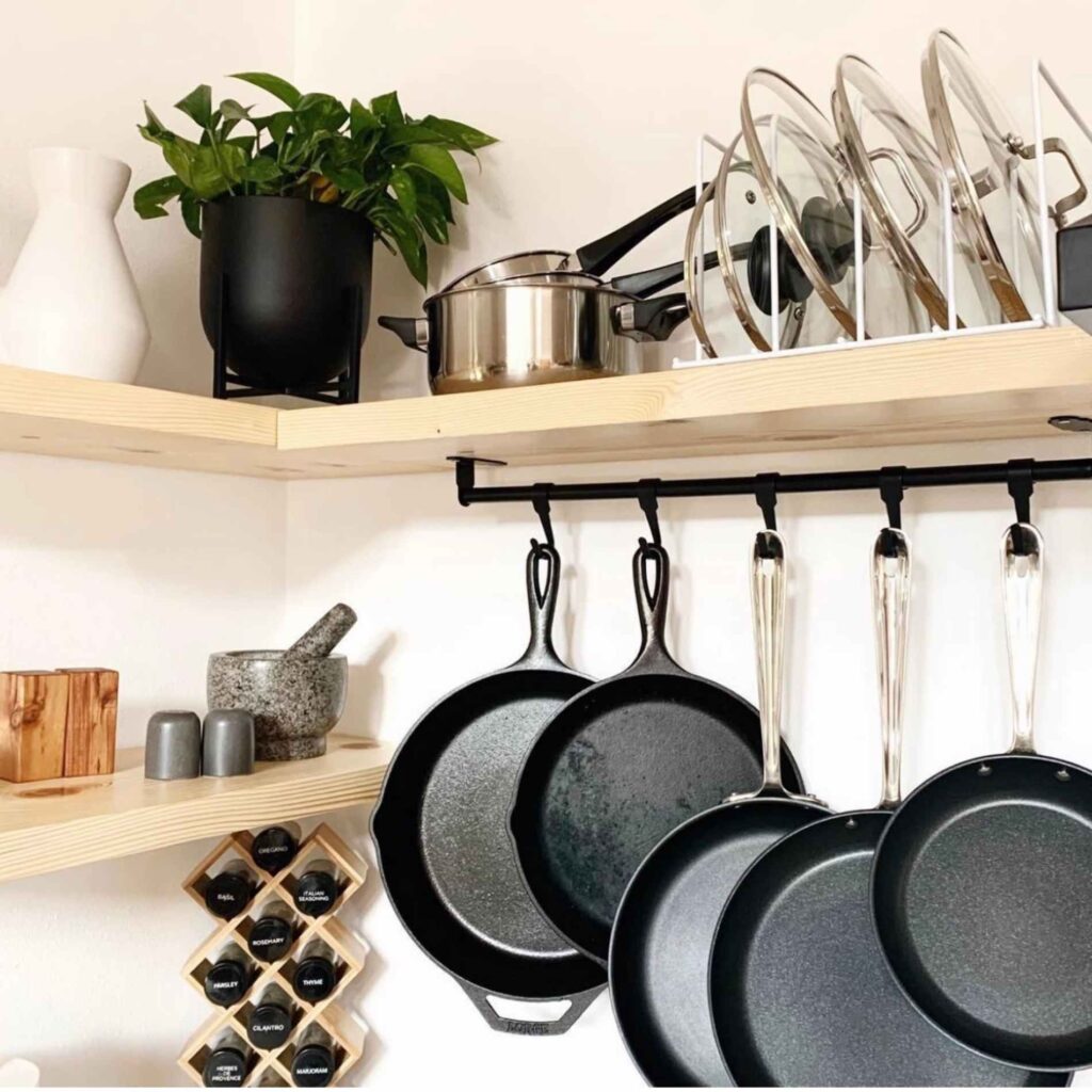 Pans, pots, and lids on a shelf system in a kitchen. 