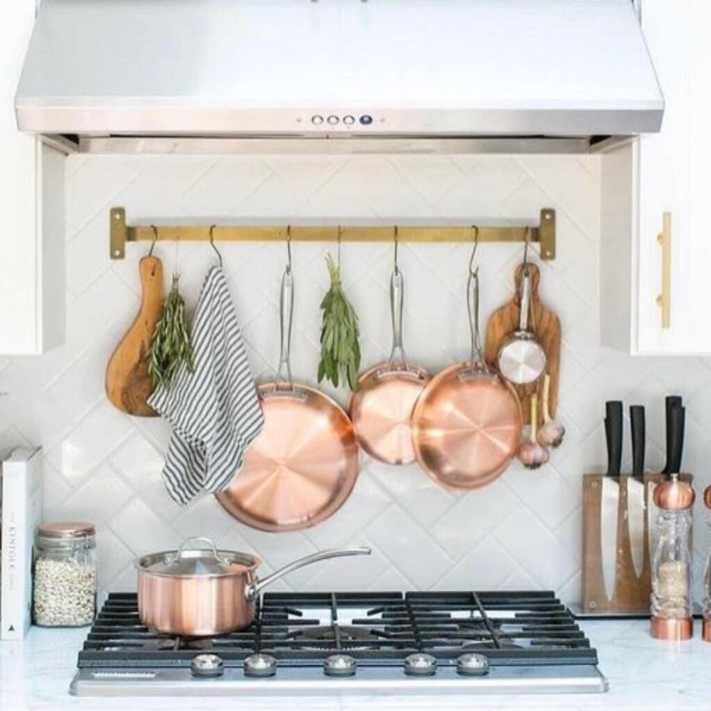 Pots and pans hanging above the stove on a rail. 