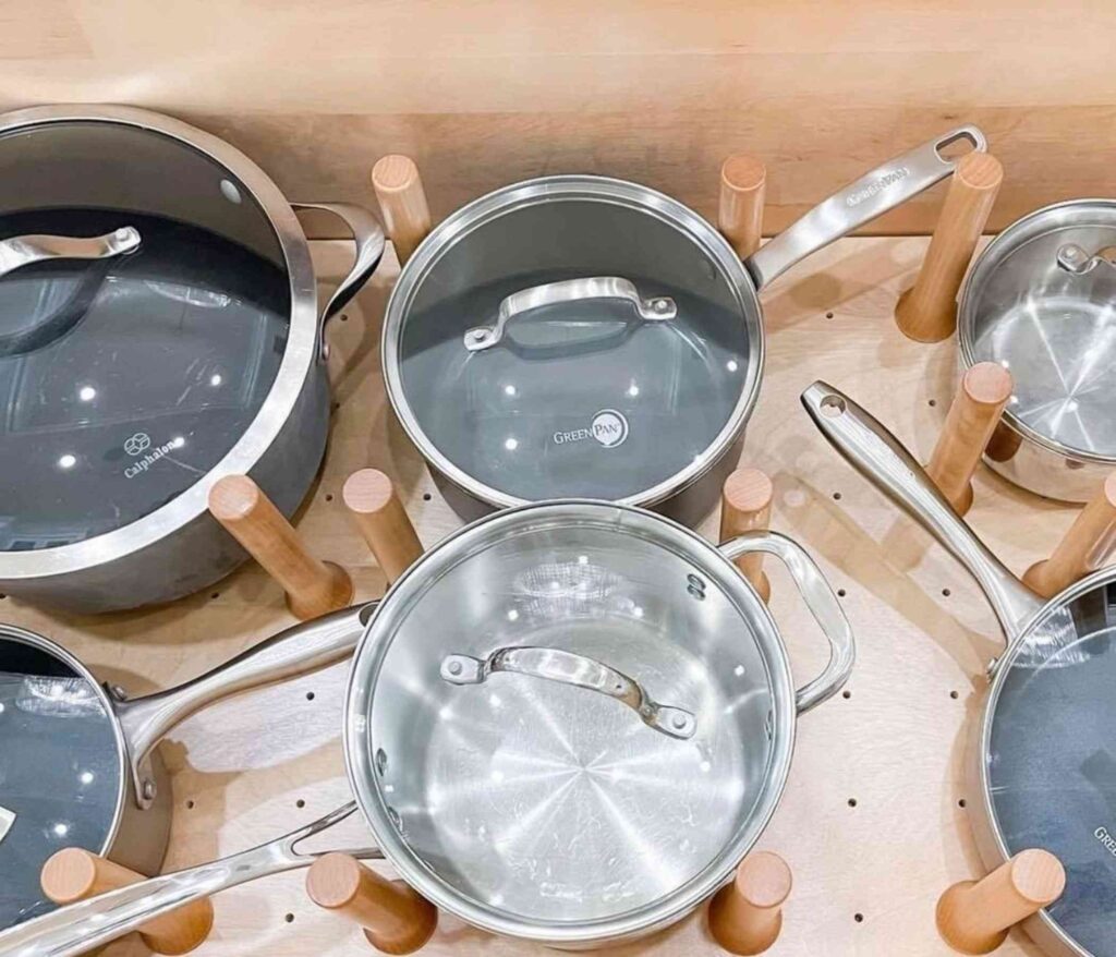 Pots and lids organized in a kitchen drawer with a peg board system 