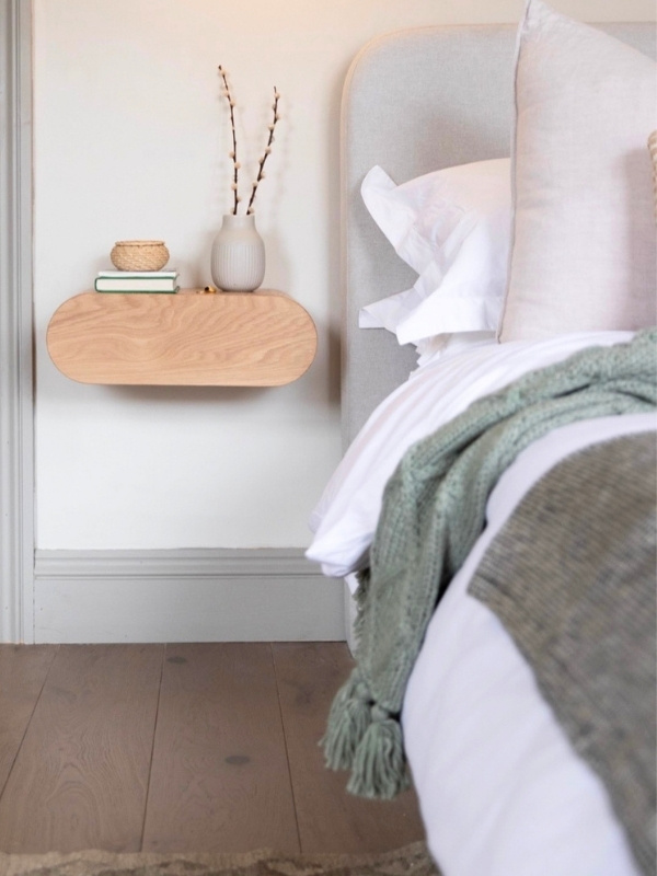 Picture of a small bedroom with a  nightstand hung on the wall. 