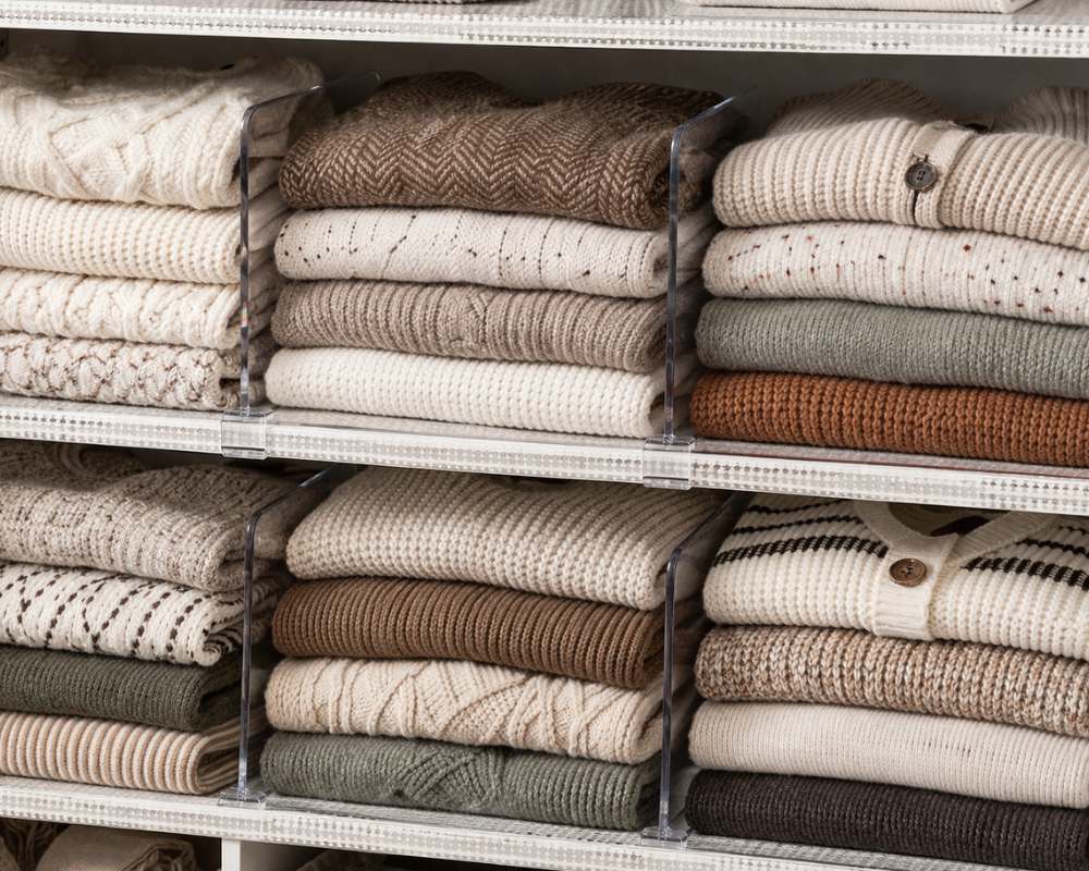 Small Bedroom closet organized with acrylic shelf dividers on shelves. 