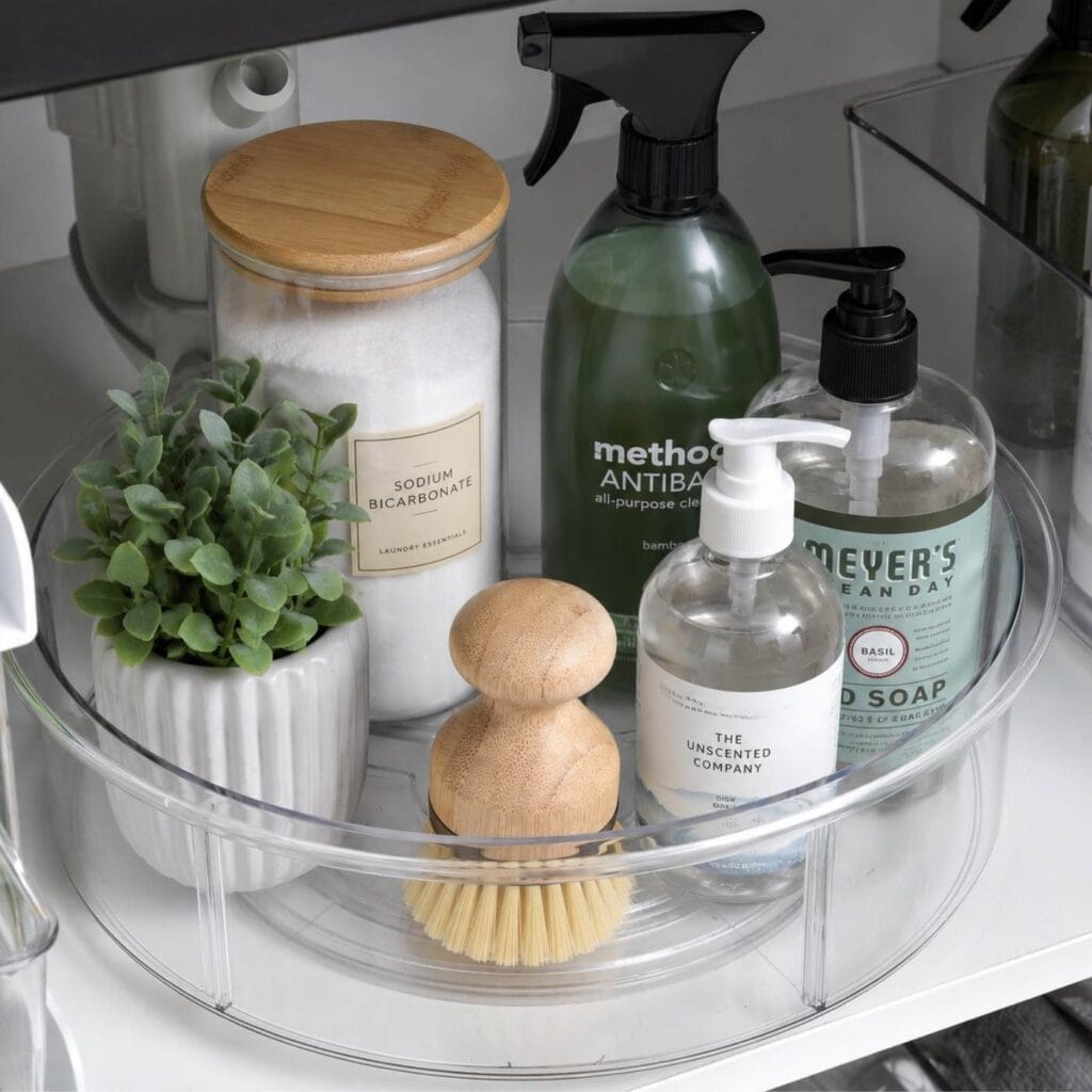 Acrylic lazy susan with cleaning products on it under a kitchen sink. 